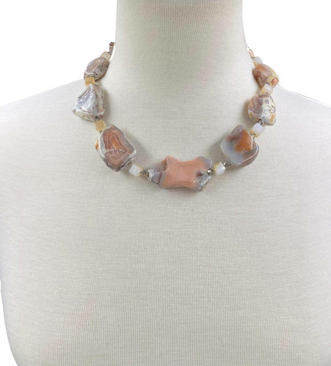 Pink Botswana Agate Necklace featuring chunky pastel gemstone beads handcrafted into a short statement necklace for women. This handmade natural crystal jewelry piece showcases soft pink and cream hues, offering calming and healing properties. Perfect as a thoughtful gift, it adds a delicate yet bold touch to any outfit. Lightweight and versatile, this unique necklace blends artisanal craftsmanship with boho elegance, ideal for everyday wear or special occasions.