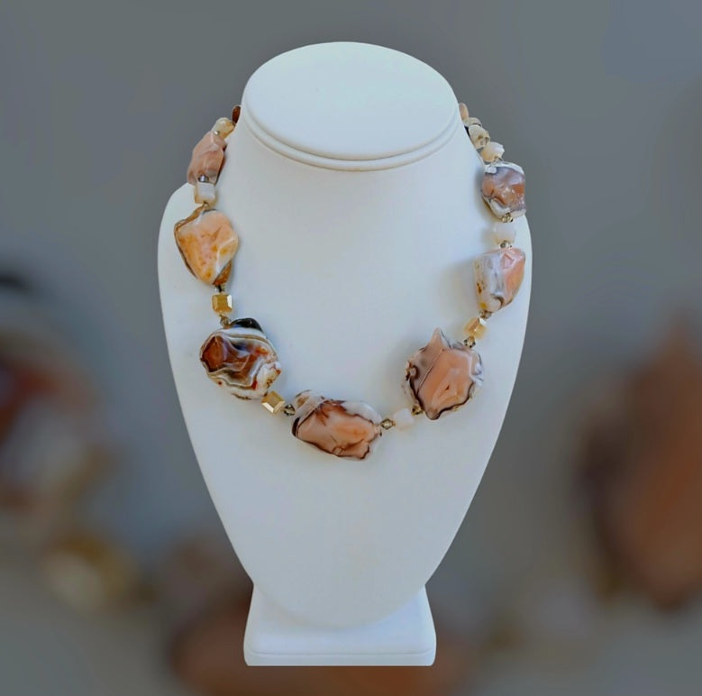 Pink Botswana Agate Necklace featuring chunky pastel gemstone beads handcrafted into a short statement necklace for women. This handmade natural crystal jewelry piece showcases soft pink and cream hues, offering calming and healing properties. Perfect as a thoughtful gift, it adds a delicate yet bold touch to any outfit. Lightweight and versatile, this unique necklace blends artisanal craftsmanship with boho elegance, ideal for everyday wear or special occasions.