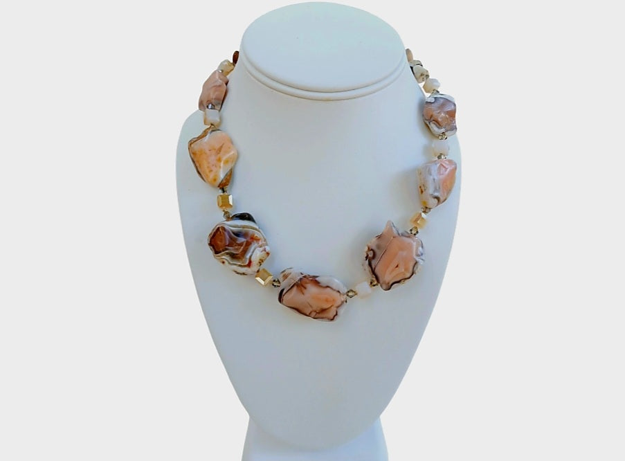Pink Botswana Agate Necklace featuring chunky pastel gemstone beads handcrafted into a short statement necklace for women. This handmade natural crystal jewelry piece showcases soft pink and cream hues, offering calming and healing properties. Perfect as a thoughtful gift, it adds a delicate yet bold touch to any outfit. Lightweight and versatile, this unique necklace blends artisanal craftsmanship with boho elegance, ideal for everyday wear or special occasions.
