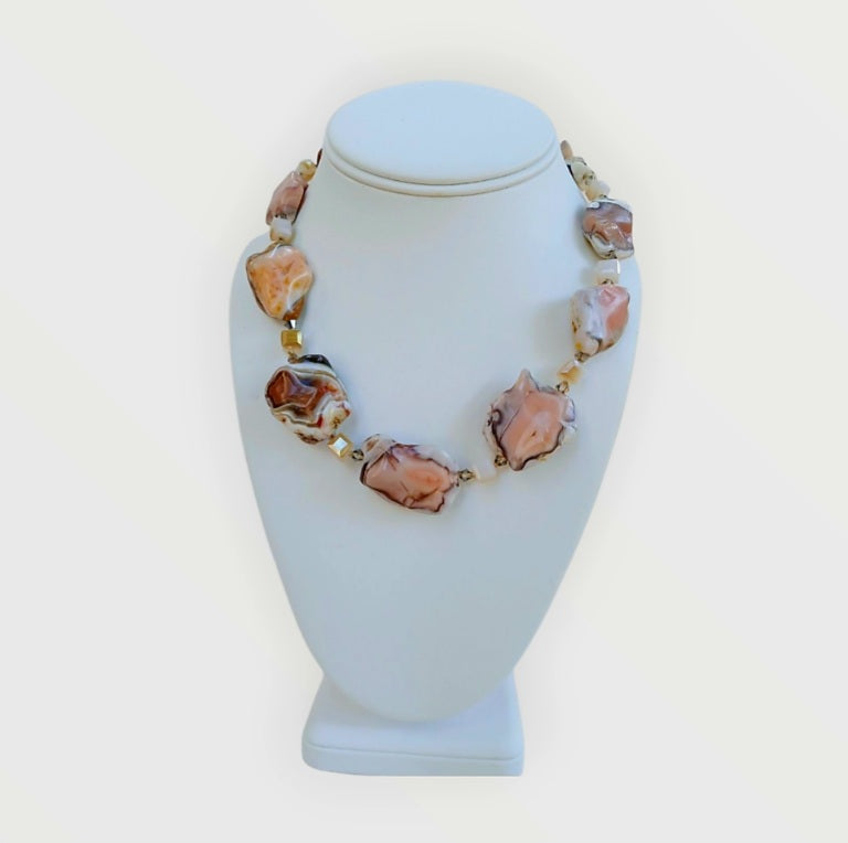 Pink Botswana Agate Necklace featuring chunky pastel gemstone beads handcrafted into a short statement necklace for women. This handmade natural crystal jewelry piece showcases soft pink and cream hues, offering calming and healing properties. Perfect as a thoughtful gift, it adds a delicate yet bold touch to any outfit. Lightweight and versatile, this unique necklace blends artisanal craftsmanship with boho elegance, ideal for everyday wear or special occasions.