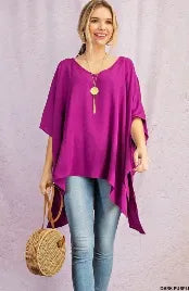 Purple V-neck drop shoulder tunic for women featuring a poncho-style design with side slits and a high-low hem. Made from soft, breathable rayon fabric, this comfortable and casual chic top offers a relaxed fit ideal for everyday wear. The versatile silhouette combines style and ease, making it perfect for layering or wearing on its own during warmer seasons or transitional weather.