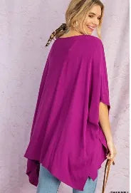 Purple V-neck drop shoulder tunic for women featuring a poncho-style design with side slits and a high-low hem. Made from soft, breathable rayon fabric, this comfortable and casual chic top offers a relaxed fit ideal for everyday wear. The versatile silhouette combines style and ease, making it perfect for layering or wearing on its own during warmer seasons or transitional weather.