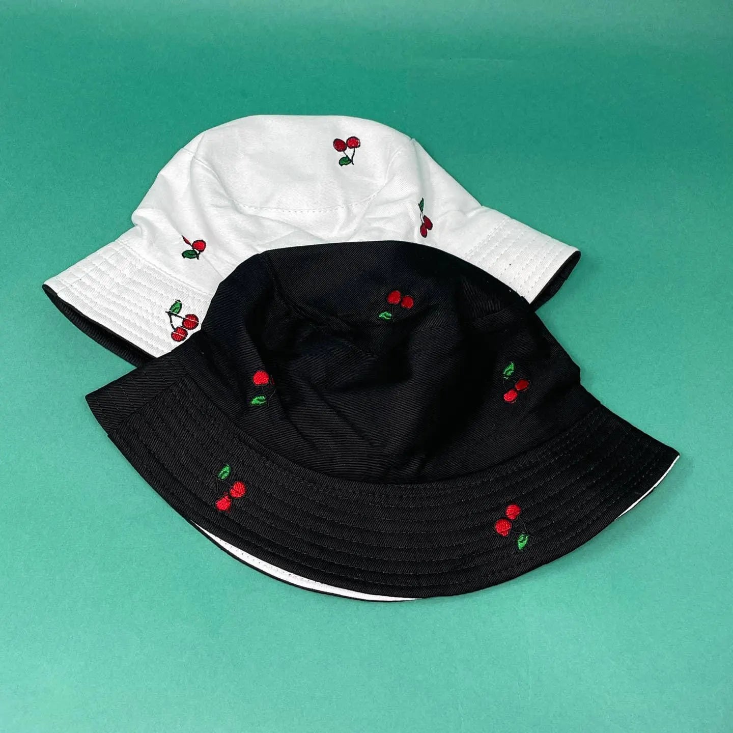 Reversible Cherry Bucket Hat for men and women featuring a fun cherry print on one side and a solid color on the other, offering two stylish looks in one. This lightweight, breathable summer hat is perfect for vacations, casual outings, beach days, and travel. Water-resistant material makes it ideal for light rain and unexpected weather. Unisex design fits most head sizes comfortably, combining fashion and function for everyday outdoor wear.