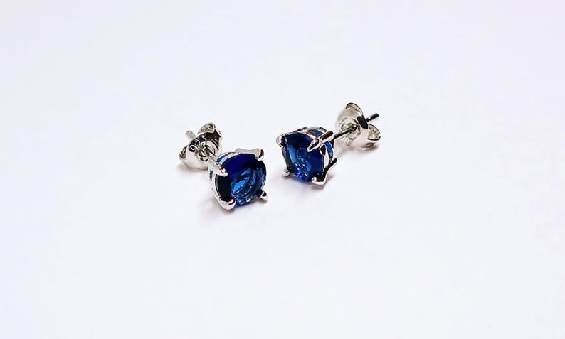 Blue Sapphire Sterling Silver Stud Earrings featuring dazzling deep blue gemstones in a minimalist setting. These elegant birthstone earrings are perfect for women who love dainty, timeless jewelry with meaningful detail. Ideal as a September birthday or anniversary gift, they offer a refined, sophisticated touch for everyday wear or special occasions.Handcrafted with care, these studs make a thoughtful gift for her, blending simplicity, elegance, and personal significance in one classic design.