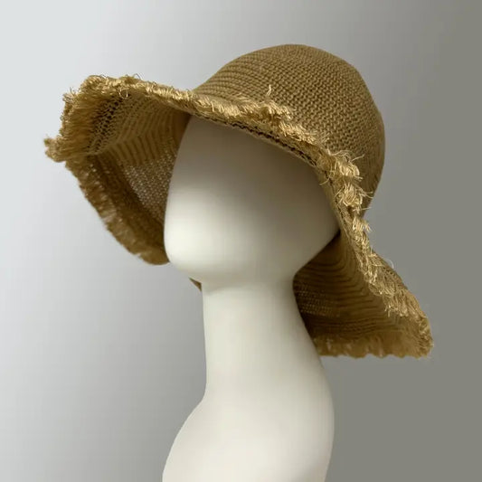 Tan Cabo Sun Hat featuring a wide brim and breathable straw construction, designed for women seeking stylish sun protection during summer beach days or travel. This foldable, lightweight hat combines comfort with practicality, perfect for vacations, outdoor activities, and everyday wear. Its classic design offers excellent sun coverage while maintaining a chic, casual look, making it an essential accessory for warm-weather adventures and sunny escapes.