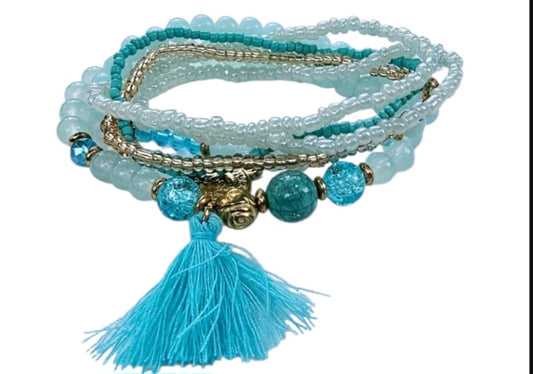 Turquoise Ocean Stacks Bracelet featuring layered blue beads, healing stones, and a playful charm tassel design. This handmade boho bracelet for women and girls offers a vibrant, beachy vibe inspired by ocean waves and coastal energy. Perfect for everyday wear, festivals, or beach vacations, it combines spiritual healing with carefree style. A thoughtful gift for her, this bohemian jewelry piece adds color, positivity, and charm to any casual or summer-inspired look.