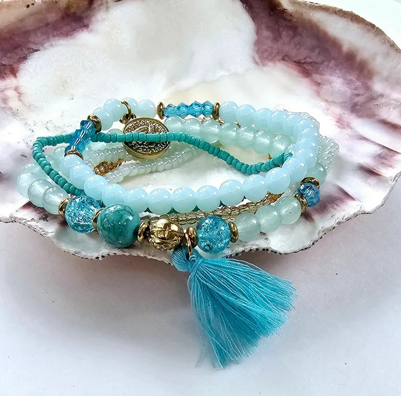 Turquoise Ocean Stacks Bracelet featuring layered blue beads, healing stones, and a playful charm tassel design. This handmade boho bracelet for women and girls offers a vibrant, beachy vibe inspired by ocean waves and coastal energy. Perfect for everyday wear, festivals, or beach vacations, it combines spiritual healing with carefree style. A thoughtful gift for her, this bohemian jewelry piece adds color, positivity, and charm to any casual or summer-inspired look.