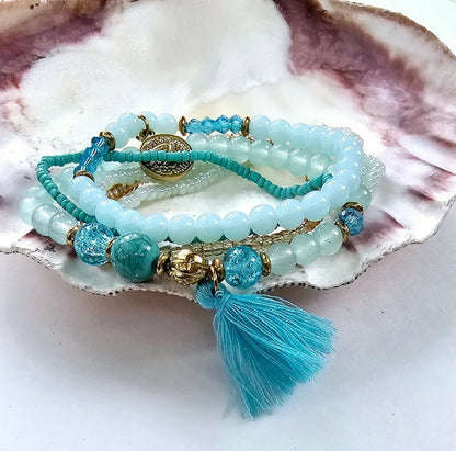 Turquoise Ocean Stacks Bracelet featuring layered blue beads, healing stones, and a playful charm tassel design. This handmade boho bracelet for women and girls offers a vibrant, beachy vibe inspired by ocean waves and coastal energy. Perfect for everyday wear, festivals, or beach vacations, it combines spiritual healing with carefree style. A thoughtful gift for her, this bohemian jewelry piece adds color, positivity, and charm to any casual or summer-inspired look.