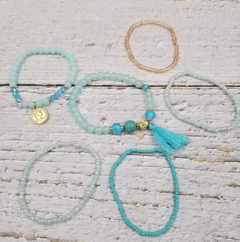 Turquoise Ocean Stacks Bracelet featuring layered blue beads, healing stones, and a playful charm tassel design. This handmade boho bracelet for women and girls offers a vibrant, beachy vibe inspired by ocean waves and coastal energy. Perfect for everyday wear, festivals, or beach vacations, it combines spiritual healing with carefree style. A thoughtful gift for her, this bohemian jewelry piece adds color, positivity, and charm to any casual or summer-inspired look.