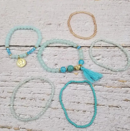 Turquoise Ocean Stacks Bracelet featuring layered blue beads, healing stones, and a playful charm tassel design. This handmade boho bracelet for women and girls offers a vibrant, beachy vibe inspired by ocean waves and coastal energy. Perfect for everyday wear, festivals, or beach vacations, it combines spiritual healing with carefree style. A thoughtful gift for her, this bohemian jewelry piece adds color, positivity, and charm to any casual or summer-inspired look.