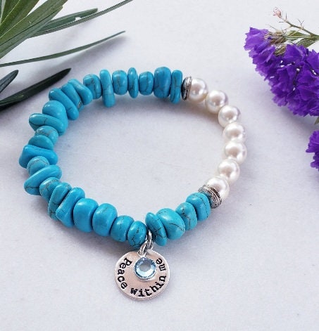 Turquoise & Freshwater Pearl Bracelet featuring a handmade design that blends vibrant turquoise stones with lustrous freshwater pearls. This inspirational healing jewelry is perfect for women seeking balance and positive energy, making it an ideal birthstone gift for December. The statement bracelet combines natural beauty and artisanal craftsmanship, adding a stylish boho touch to any outfit. Lightweight and elegant, it’s suitable for everyday wear or special occasions.