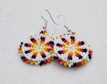Handmade white and yellow beaded earrings in native ethnic style, featuring intricate tribal medallion design. These artisan statement earrings are perfect for women who appreciate unique, handcrafted jewelry inspired by traditional tribal patterns. Lightweight and bold, they make an excellent gift and add a touch of cultural elegance to any outfit, ideal for everyday wear or special occasions with a vibrant ethnic flair.