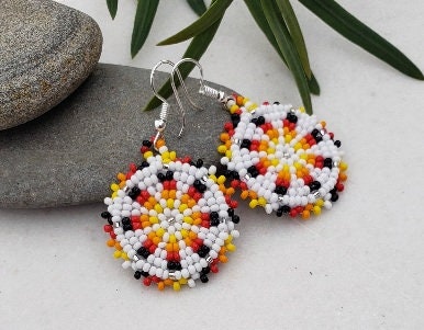 Handmade white and yellow beaded earrings in native ethnic style, featuring intricate tribal medallion design. These artisan statement earrings are perfect for women who appreciate unique, handcrafted jewelry inspired by traditional tribal patterns. Lightweight and bold, they make an excellent gift and add a touch of cultural elegance to any outfit, ideal for everyday wear or special occasions with a vibrant ethnic flair.