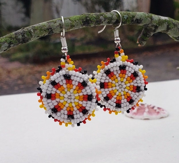 Handmade white and yellow beaded earrings in native ethnic style, featuring intricate tribal medallion design. These artisan statement earrings are perfect for women who appreciate unique, handcrafted jewelry inspired by traditional tribal patterns. Lightweight and bold, they make an excellent gift and add a touch of cultural elegance to any outfit, ideal for everyday wear or special occasions with a vibrant ethnic flair.